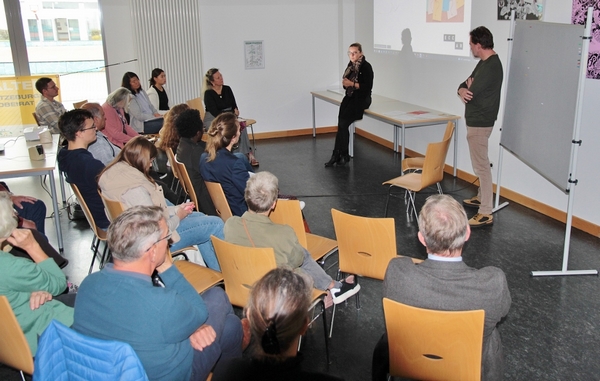 Das Bild zeigte eine sitzende Gruppe von Menschen, die dem Vortrag einer von Sandra Rickert von der Hansestadt Lübeck aufmerksam folgen.